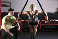 fit looking woman working out with trainer beside her