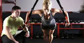 fit looking woman working out with trainer beside her